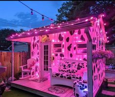 a small pink house with lights on it's roof and furniture in the yard