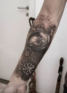 a man's arm with a compass tattoo on it and a pocket watch in the middle