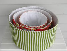 three round baskets are stacked on top of each other in green and white striped fabric