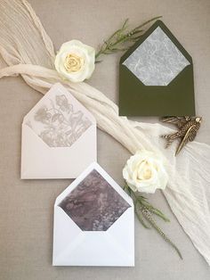 three envelopes with white roses and greenery