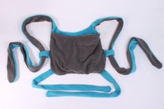 a gray and blue baby carrier sitting on top of a white table next to it's strap