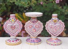 three colorful vases sitting on top of a table next to each other with hearts painted on them