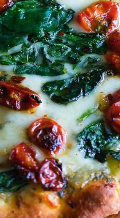 a pizza with tomatoes, spinach and cheese on it