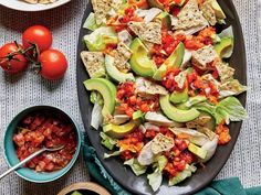 a platter filled with salad and tortilla chips next to two bowls of salsa