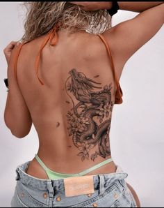 the back of a woman's body with tattoos on her upper and lower back