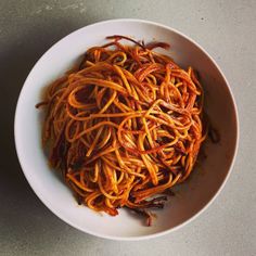 a white bowl filled with spaghetti on top of a table