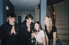 four young people standing in front of a staircase making the v sign with their hands