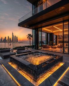 an outdoor living area with a fountain in front of the ocean and cityscape