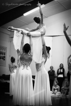 two women in white dresses are doing acrobatic tricks