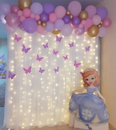 a room decorated with balloons, lights and a princess sitting on a chair in front of a curtain