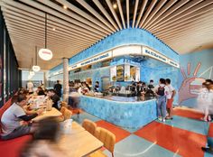 people sitting at tables in a restaurant with blue walls and red checkered flooring