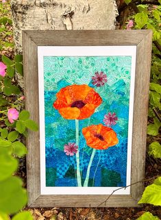 an image of two orange flowers on a blue and green background in a wood frame