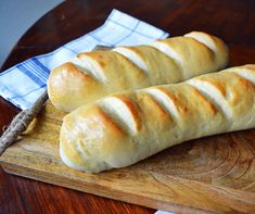 two loaves of bread sitting on top of a wooden cutting board