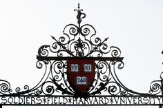 an ornate iron gate with a red and white sign underneath it that reads soldested harvard university