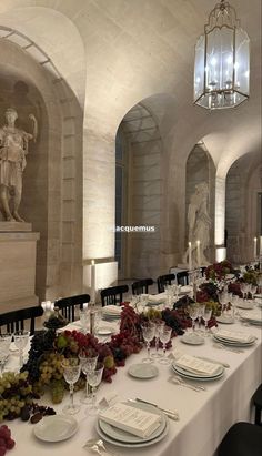 a long table is set with white plates and place settings for an elegant dinner party