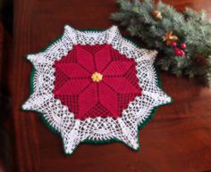 a crocheted doily sits on a table next to a christmas tree branch