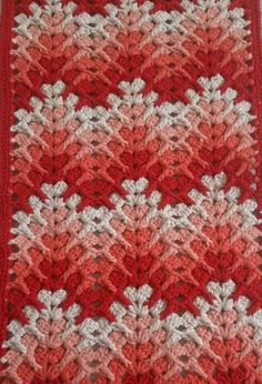 a red and white crocheted afghan with leaves on it