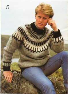 a woman sitting on top of a rock wearing a sweater