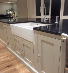 a kitchen with white cabinets, black counter tops and wooden floors is pictured in this image