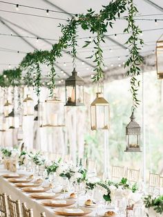 a long table is set with place settings and hanging lanterns