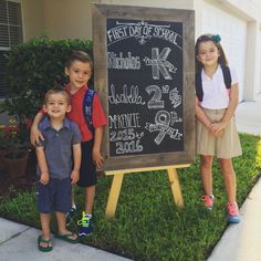 three young children standing in front of a chalkboard with numbers on it and the words first day of school written on it