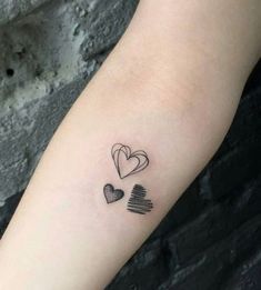 a small heart tattoo on the left forearm and right arm with two hearts in it