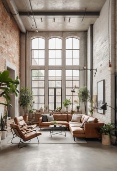 an industrial living room with brick walls and large windows, leather couches and chairs