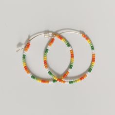 Colorful glass tropical, orange, green, and white beads adorn a gold hoop earring. These are lightweight and versatile earrings. Beach Hoop Earrings With Tiny Beads, Multicolor Hoop Earrings With Round Beads, Trendy Summer Hoop Earrings With Tiny Beads, Summer Beach Hoop Earrings With Tiny Beads, Beach Hoop Earrings With Dangling Beads, Festival Rainbow Beaded Hoop Earrings, Bohemian Large Beads Multicolor Hoop Earrings, Festival Multicolor Tiny Beads Hoop Earrings, Bohemian Multicolor Hoop Earrings With Large Beads