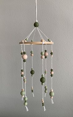 a green and white mobile hanging from the ceiling with beads on it's sides