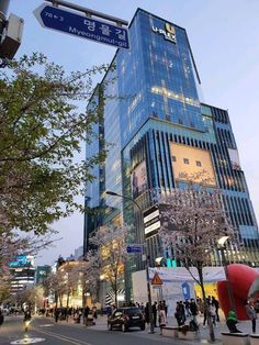 people are standing on the street corner in front of a tall building with many windows