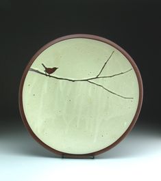 a white plate with a bird sitting on a tree branch in the middle of it