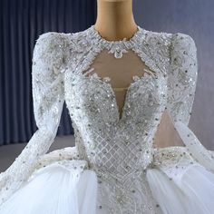 a white wedding dress on display in front of a curtain