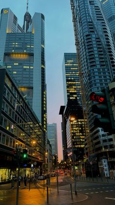 a city street at dusk with tall buildings and traffic lights in the foreground,