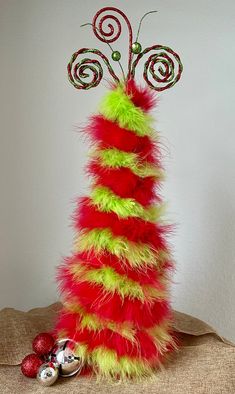 a tall red and green christmas tree with candy canes on it's top