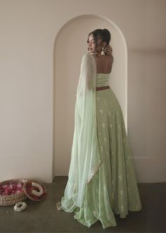 I think we just found your new mehendi set! Ira is an enchanting sage green 3-piece gotta patti lehenga set. The ensemble comes with an intricately embroidered skirt, a chic cowl neck blouse, and a matching chiffon dupatta with a gotta patti border. Ira embodies timeless elegance and contemporary allure. Blouse, lehenga, and dupatta included. Green Chikankari Embroidery Lehenga For Reception, Elegant Pista Green Dupatta With Mirror Work, Pista Green Semi-stitched Dupatta For Party, Transitional Pista Green Semi-stitched Dupatta, Gotta Patti Lehenga, Green Hand Embellished Semi-stitched Dupatta, Green Semi-stitched Embroidered Dupatta, Indian Lehenga Choli, Embellished Skirt