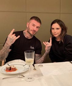 a man and woman sitting at a table in front of a plate with food on it