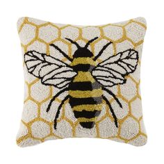 a yellow and black pillow with a bee on it's back, in front of a white background