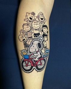 a person with a tattoo on their arm and leg, has a cartoon character riding a bike