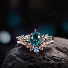 a green ring sitting on top of a rock next to a black background with white and blue stones