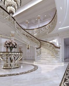 a grand staircase with chandelier and flowers in vases on the table next to it