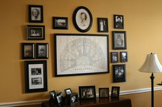 a living room wall with many pictures and framed photos on the wall, along with a lamp