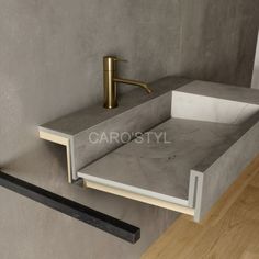 a bathroom sink made out of concrete and gold faucet