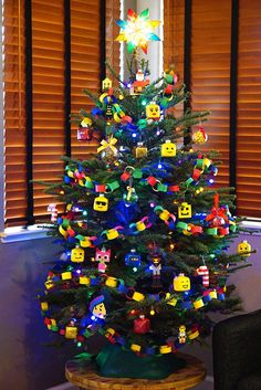 a brightly colored christmas tree with legos on it's top and decorations around the base