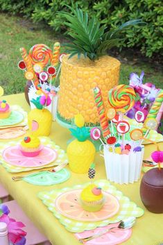 a table topped with lots of colorful desserts and candies next to a pineapple