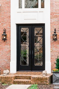 a black double door with glass and brick steps leading up to the front entryway