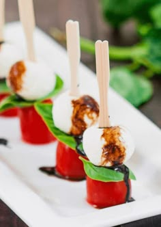 small appetizers with toothpicks are on a white plate