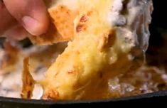 someone is dipping cheese on top of some food in a skillet and it's being held up to the camera