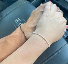 a woman's hand on the steering wheel of a car holding onto her bracelet