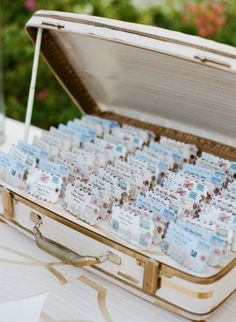 an open suitcase filled with lots of cards on top of a white table covered in flowers