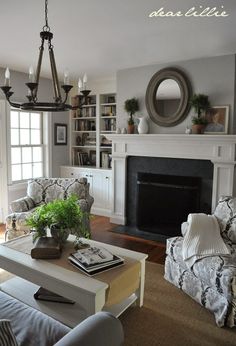 a living room filled with furniture and a fire place under a chandelier in front of a fireplace